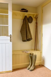 Boot room with green wellies and jacket hanging up