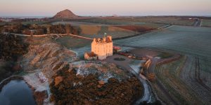 Aerial view of Fenton Tower in winter with view of North Berwick Law in background.